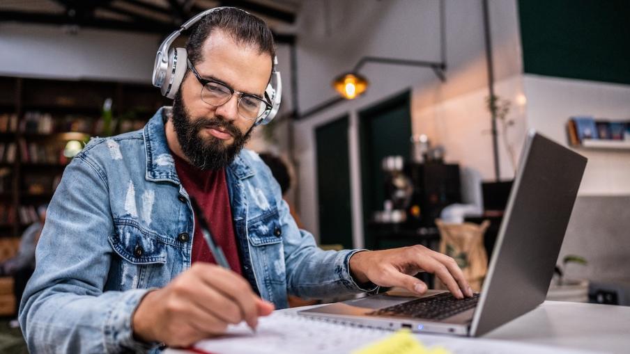 
		Ein Mann mit Kopfhörern sitzt am Laptop
	